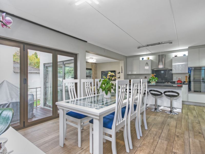 Open-plan kitchen and dining area featuring modern cabinetry, integrated oven, and glass sliding doors leading to an outdoor patio.