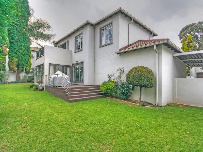 Rear view of the townhouse featuring a raised timber deck, sliding glass doors, and a well-maintained private garden area.