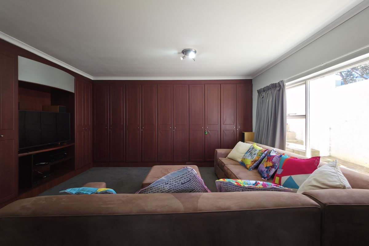 Spacious living room featuring extensive floor-to-ceiling built-in wooden cabinetry and large windows providing natural light.