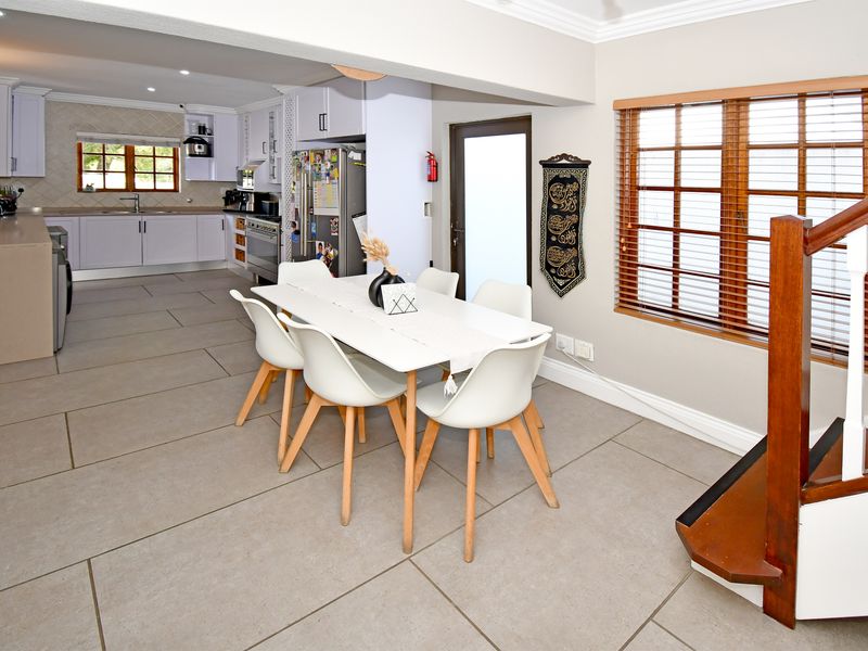 Spacious open-plan kitchen and dining area featuring modern cabinetry, tiled flooring, and a wooden staircase leading to the upper level.