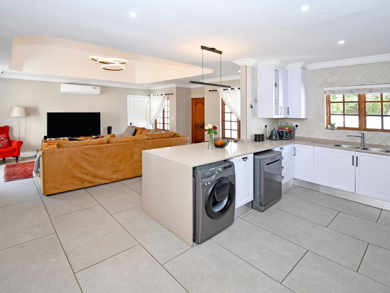 Spacious open-plan living area featuring a modern kitchen with a central island, sleek cabinetry, and tiled flooring, seamlessly flowing into the comfortable lounge space.