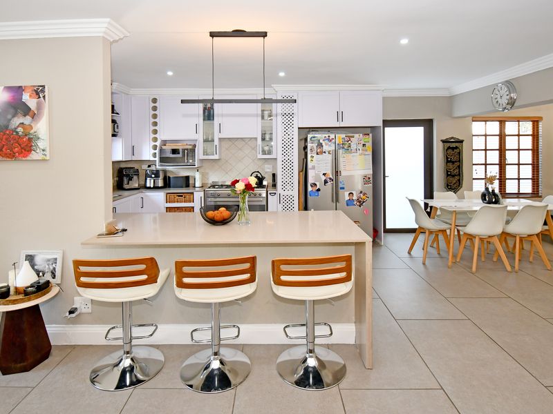 Open-plan kitchen and dining area featuring a central island, modern cabinetry, tiled flooring, and recessed lighting, creating a functional and cohesive living space.