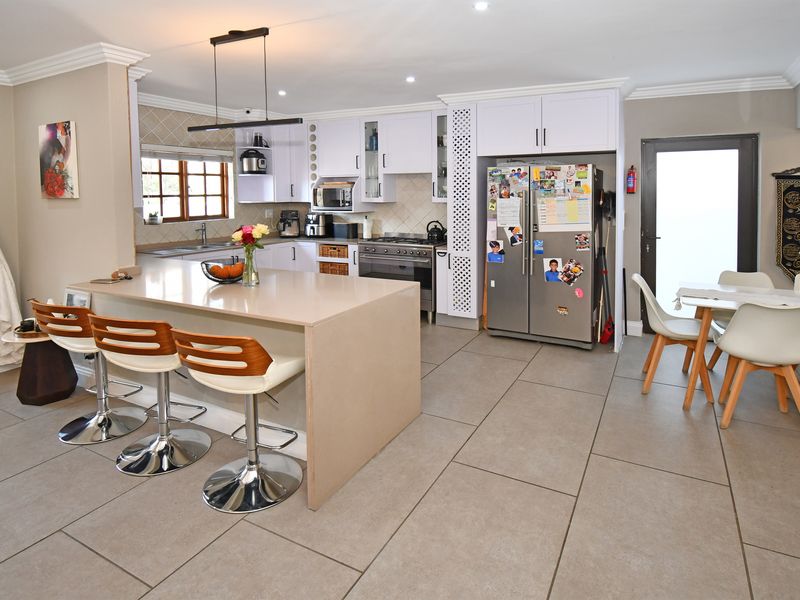 Spacious open-plan kitchen featuring a large central island with breakfast bar seating, modern cabinetry, tiled flooring, and integrated appliances.