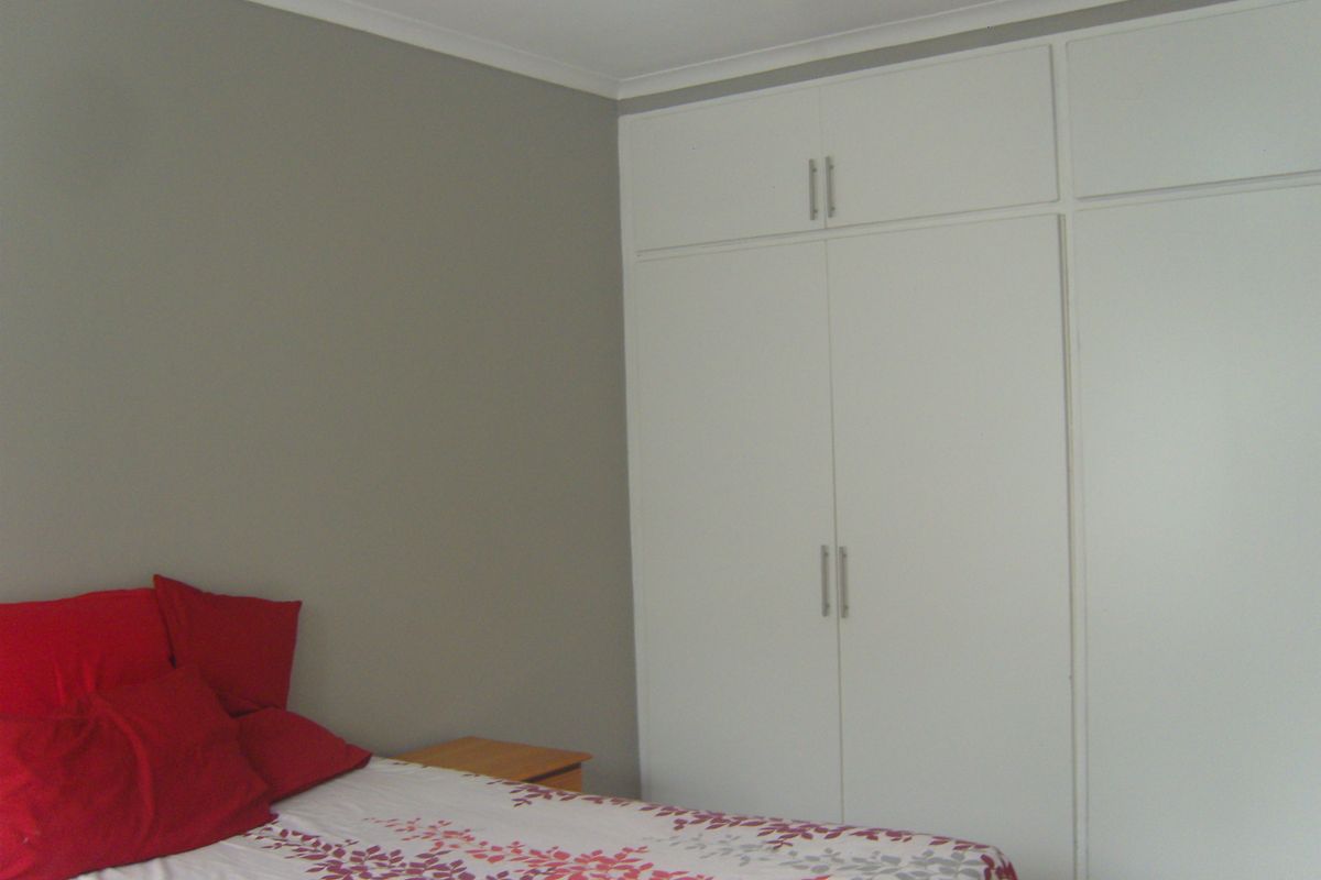 A bedroom featuring neutral wall tones and ample built-in cupboard storage with a clean, functional layout.