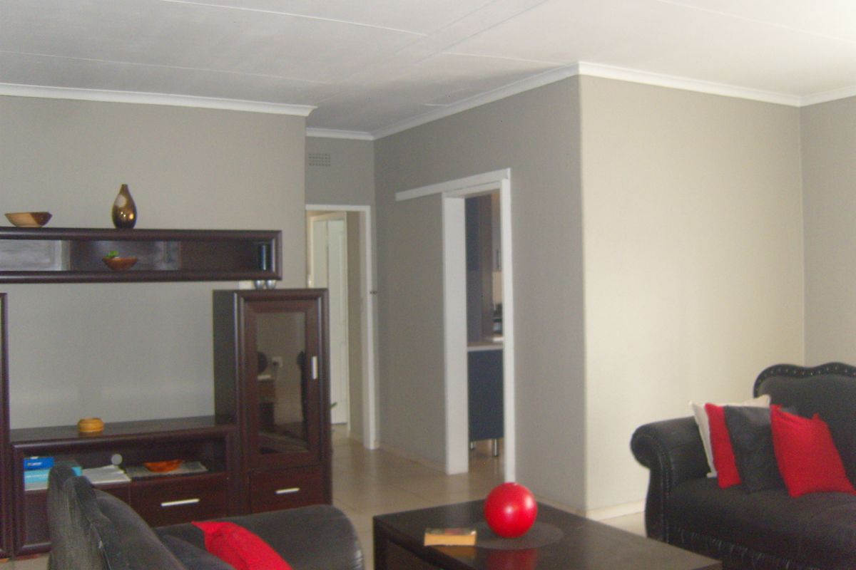 A living room featuring neutral wall tones, tiled flooring, and a sliding door leading to an adjacent space.