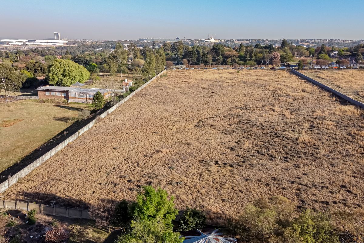 An aerial view of a large, vacant residential plot enclosed by perimeter walls, offering a clear perspective of the land and surrounding neighborhood.