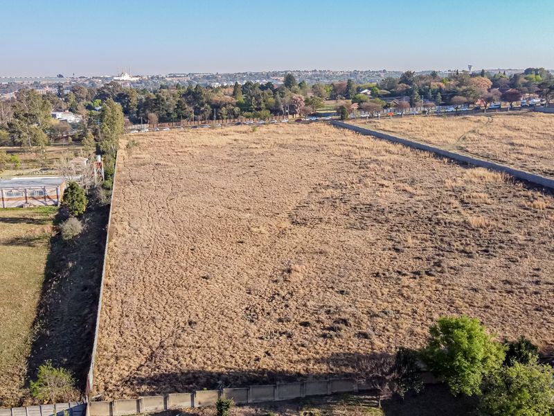 Aerial view of a large, vacant residential plot of land enclosed by perimeter walls, situated in an established suburban area.