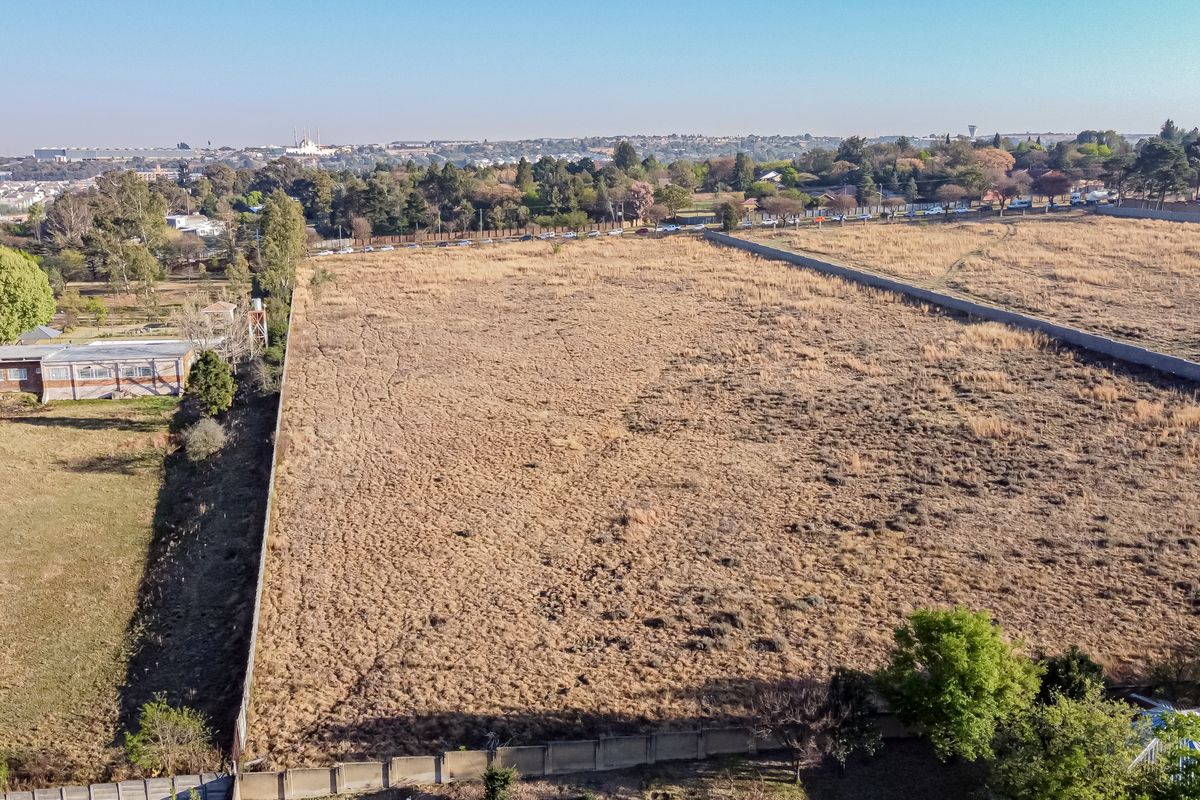 Aerial view of a large, vacant residential plot of land enclosed by perimeter walls, situated in an established suburban area.