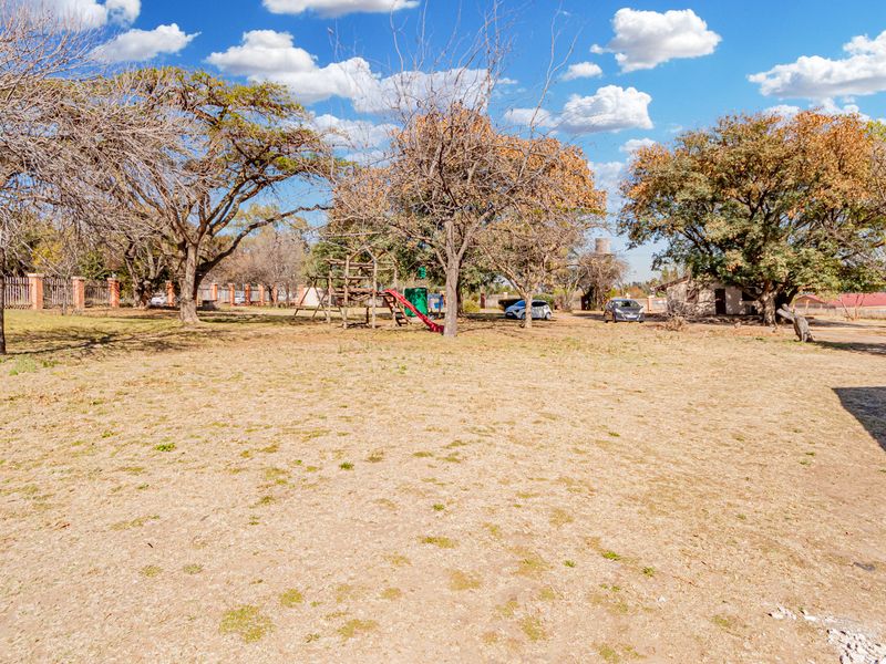 A spacious, open garden area featuring mature trees and perimeter fencing, offering significant potential for landscaping and outdoor development.