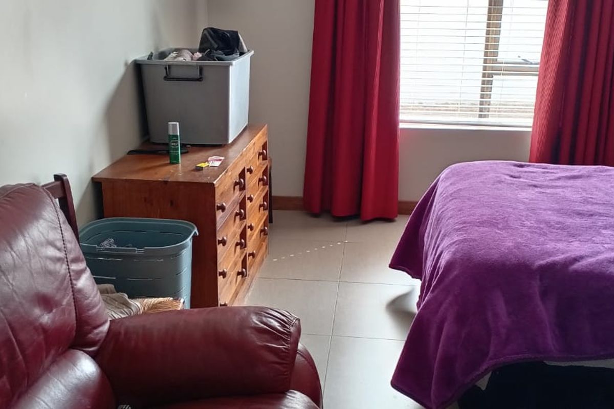 A bedroom featuring tiled flooring and window blinds, providing a functional space with natural light.
