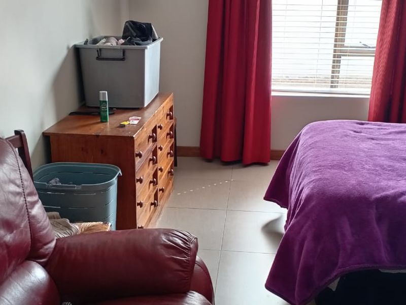 A bedroom featuring tiled flooring and window blinds, providing a functional space with natural light.