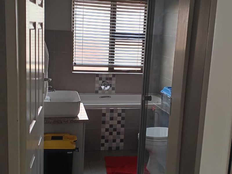 A functional bathroom featuring a vessel sink vanity, a bathtub with tiled surround, a separate shower enclosure, and a toilet.