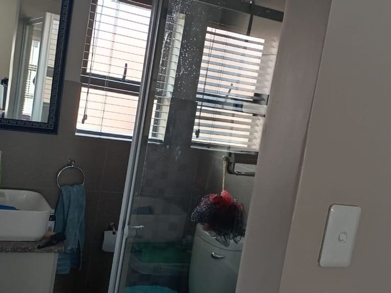 A functional bathroom featuring a vessel sink on a granite-topped vanity, a glass shower enclosure, and tiled wall finishes.