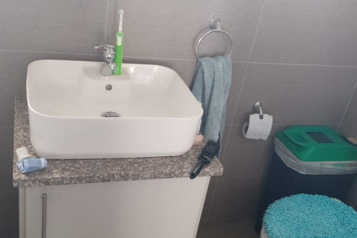 A compact bathroom featuring a modern vessel sink on a vanity cabinet, tiled walls, and a standard toilet.