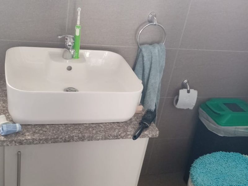 A compact bathroom featuring a modern vessel sink on a vanity cabinet, tiled walls, and a standard toilet.