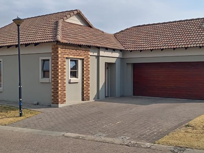 Front elevation of a modern single-story house featuring a tiled roof, brick detailing, paved driveway, and an integrated garage.