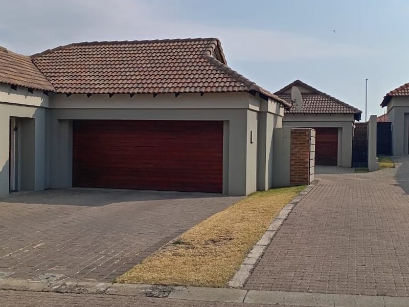 Front view of the property featuring multiple garages with wooden sectional doors, paved driveway, and well-maintained tiled roof architecture.