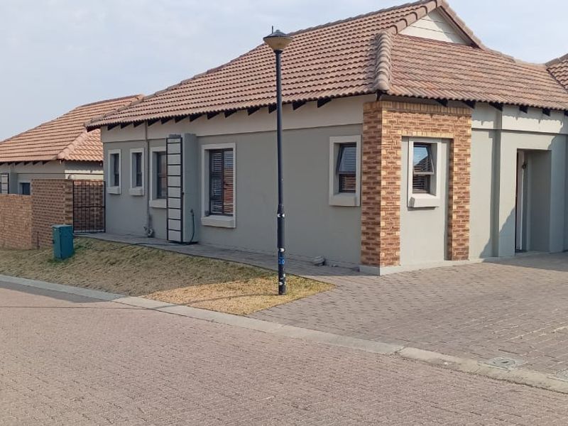 A well-maintained single-story residential property featuring a tiled roof, brick accents, and a paved driveway with an integrated garage.