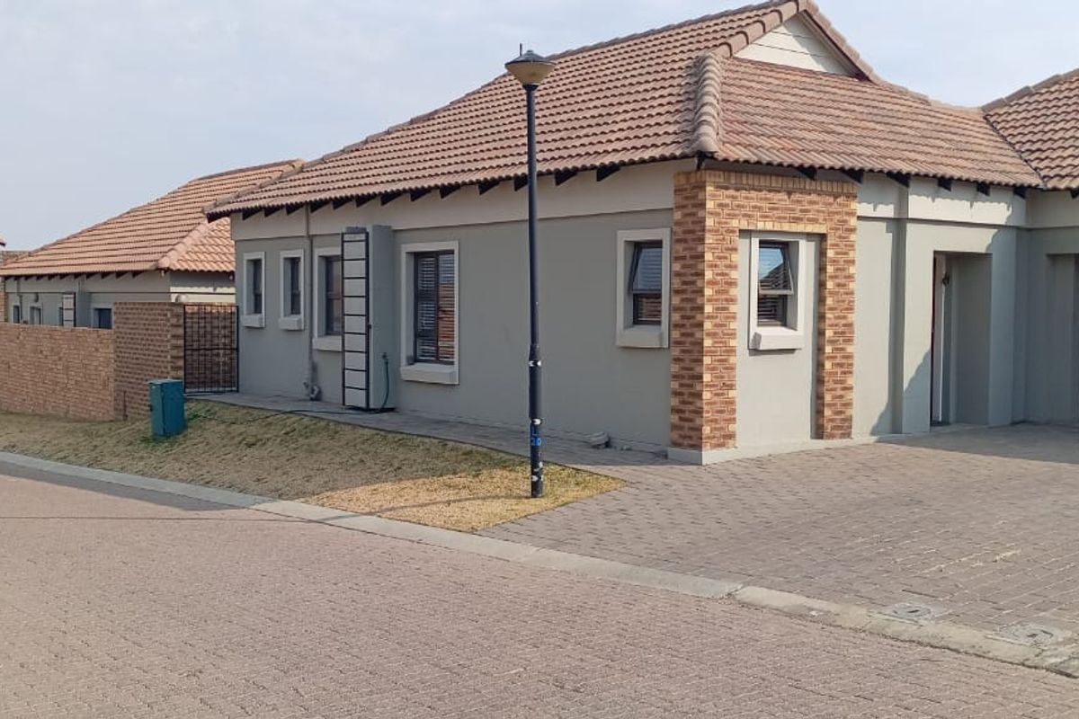 A well-maintained single-story residential property featuring a tiled roof, brick accents, and a paved driveway with an integrated garage.
