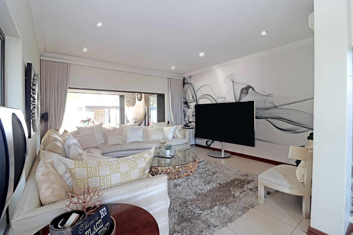 Spacious living room featuring tiled flooring, recessed downlights, and large sliding glass doors providing seamless access to the outdoor area.