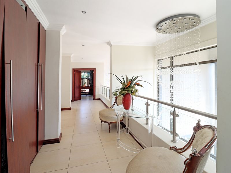Spacious upper-level hallway featuring tiled flooring, built-in wooden cabinetry, and a modern glass balustrade overlooking the lower level.