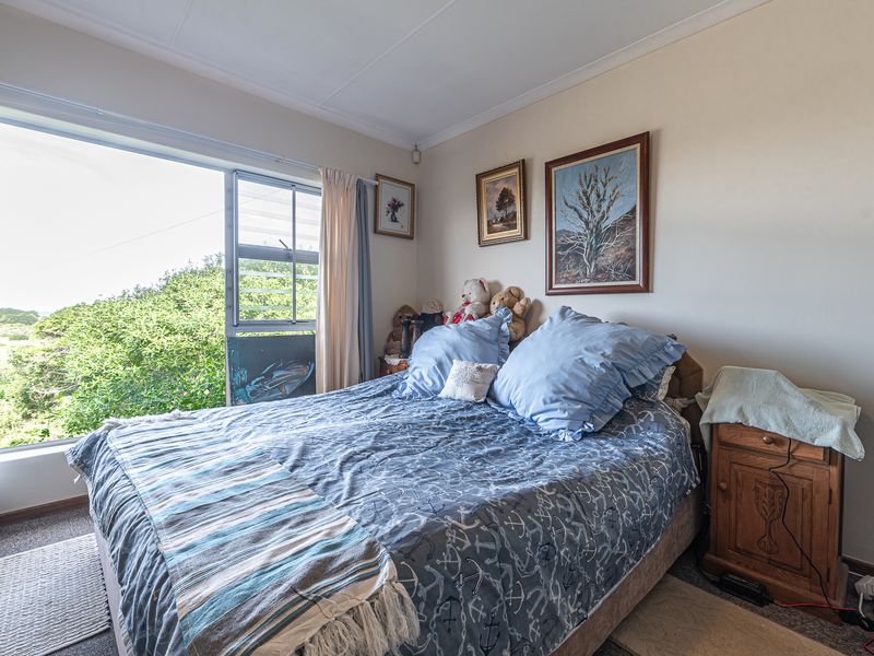 A bedroom featuring a large sliding window that provides natural light and views of the surrounding greenery.