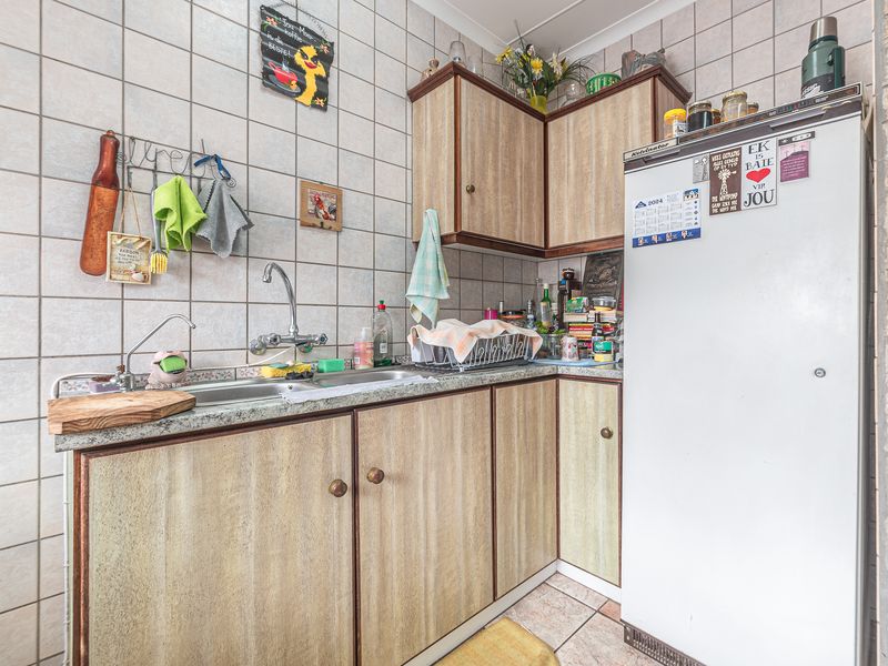 Compact scullery area featuring laminate cabinetry, a double basin sink with mixer tap, and full-height tiled splashbacks.