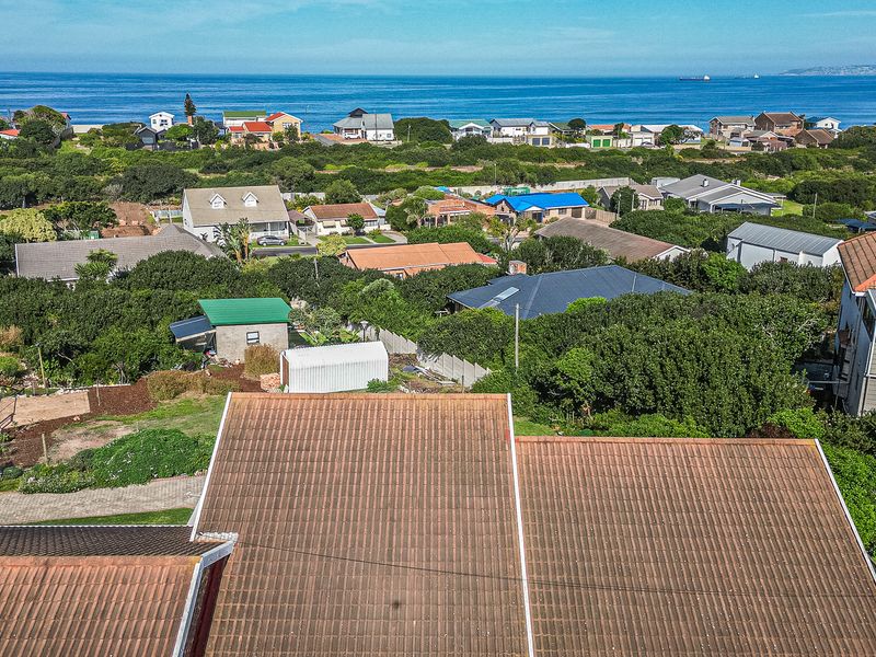 Aerial view of the property roofline overlooking the surrounding coastal neighbourhood and ocean horizon.
