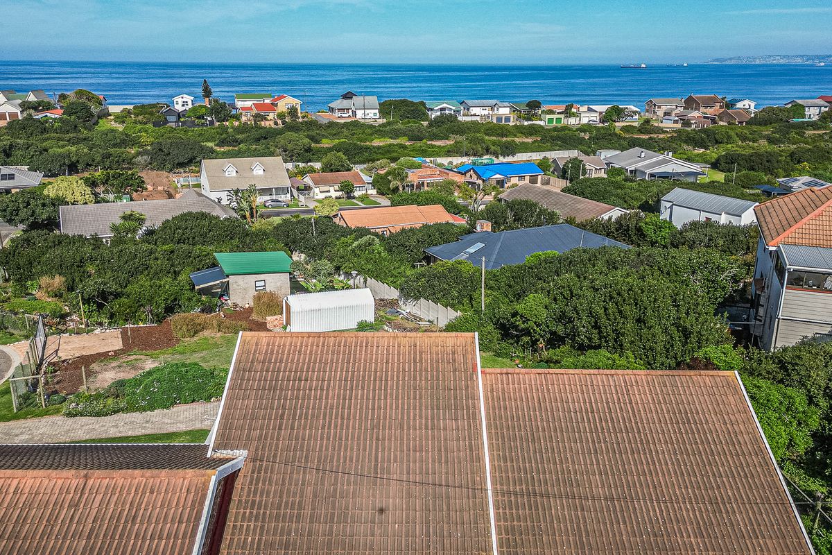 Aerial view of the property roofline overlooking the surrounding coastal neighbourhood and ocean horizon.