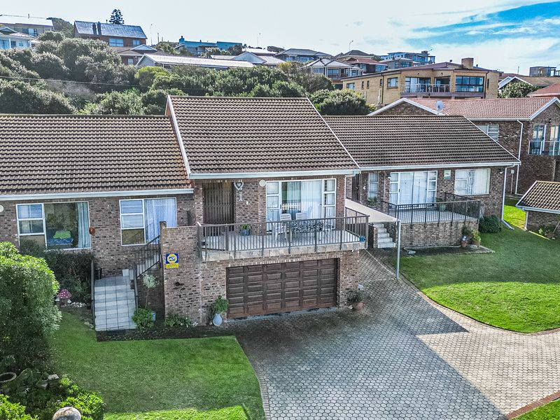 Aerial view of a brick duet property featuring a paved driveway, tiled roof, and elevated balconies set within a landscaped residential area.