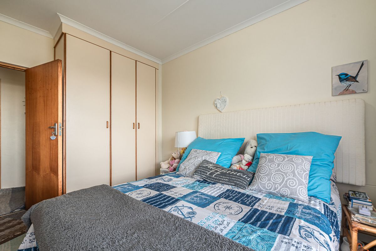 A functional bedroom featuring built-in cupboards, neutral wall finishes, and classic cove cornicing, providing a comfortable and practical living space.