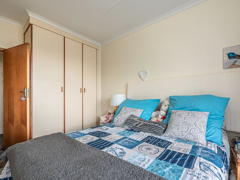 A functional bedroom featuring built-in cupboards, neutral wall finishes, and classic cove cornicing, providing a comfortable and practical living space.