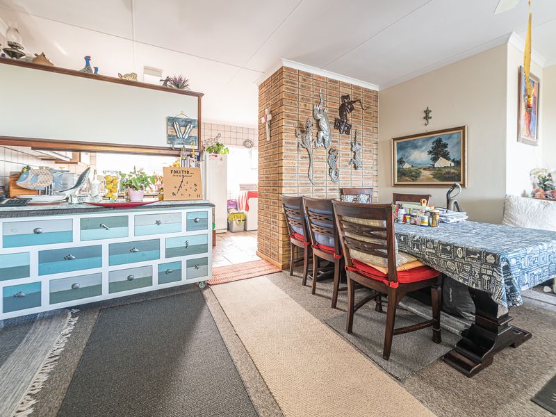 Open plan living and dining area featuring an exposed brick pillar and tiled flooring, providing a functional layout for daily living.