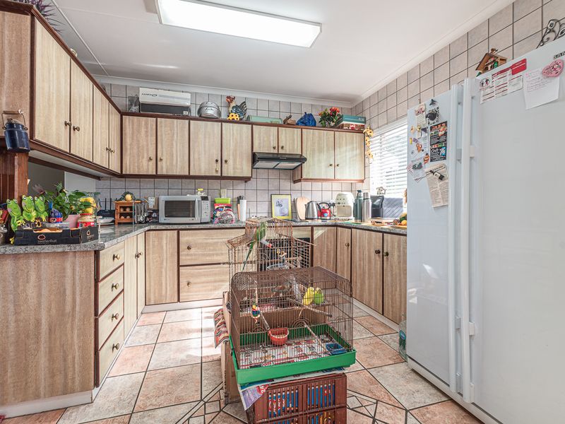 A functional kitchen featuring laminate cabinetry, granite countertops, and ceramic tiling throughout, offering a practical layout for daily meal preparation.