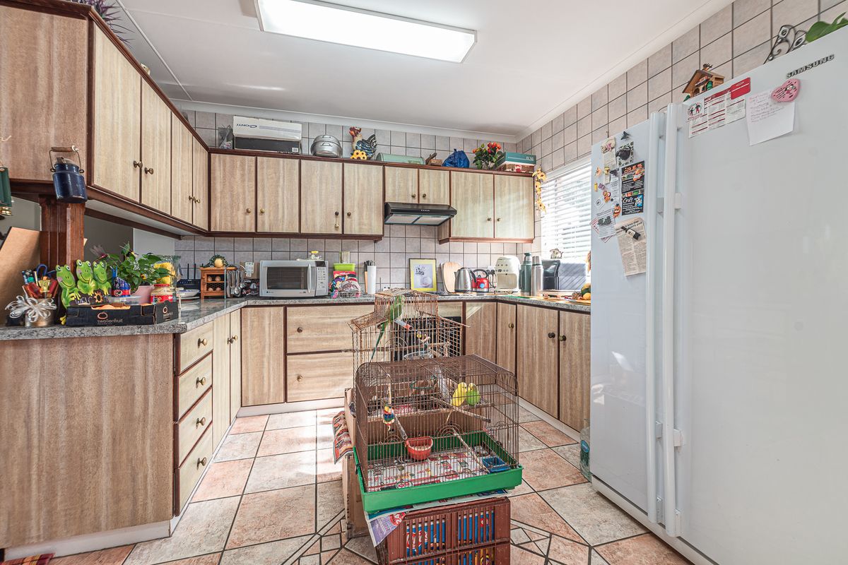 A functional kitchen featuring laminate cabinetry, granite countertops, and ceramic tiling throughout, offering a practical layout for daily meal preparation.