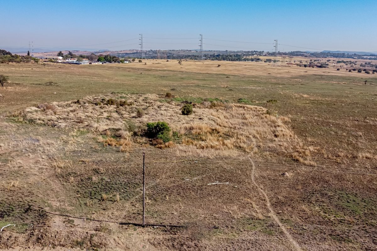 An aerial view of a large, undeveloped residential plot featuring natural grassland and a utility pole.