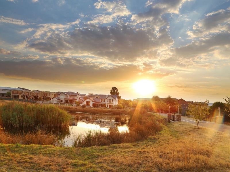A scenic sunset view overlooking a tranquil pond and surrounding residential estate landscape.