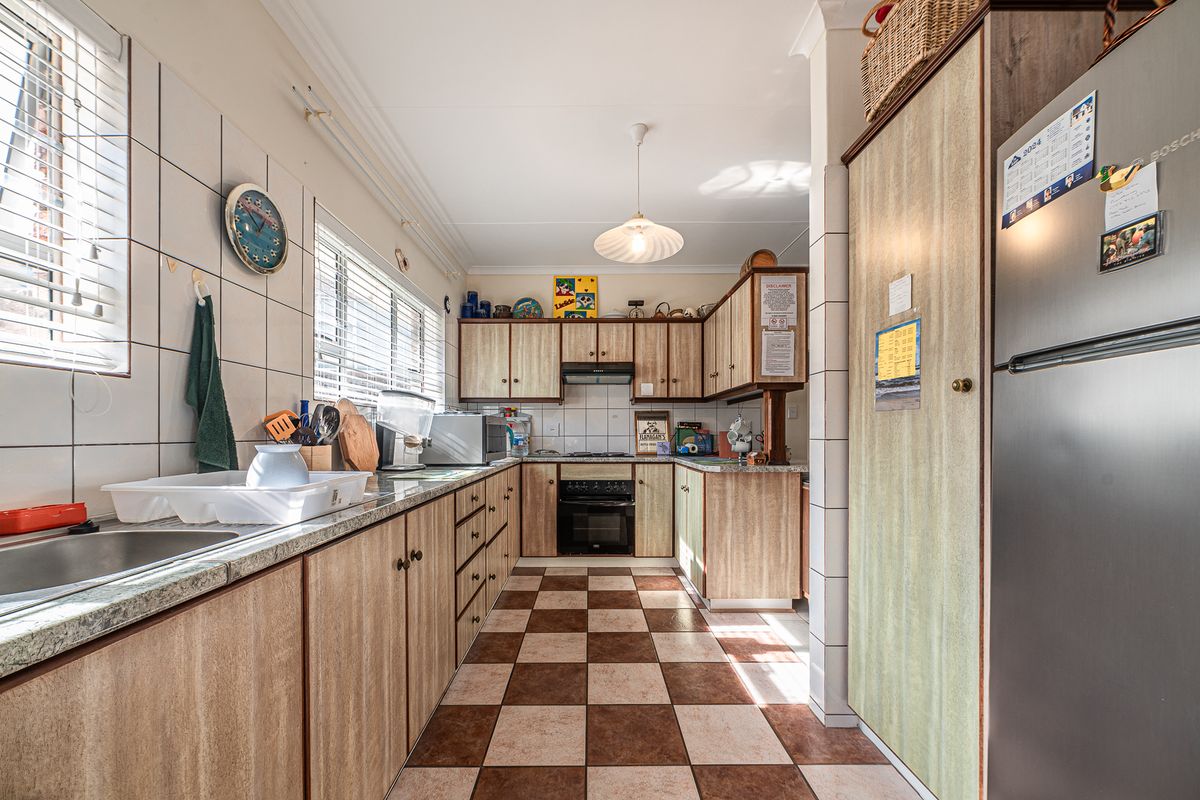 A functional kitchen featuring laminate cabinetry, granite countertops, a built-in oven with extractor fan, and a classic checkerboard tiled floor.