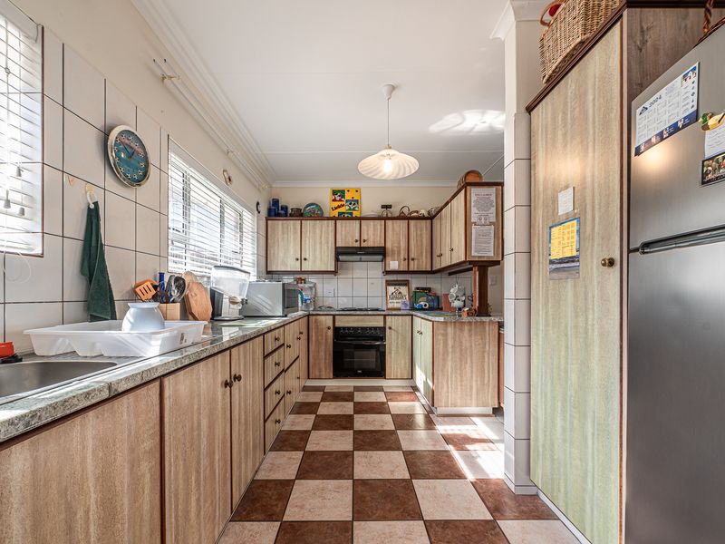 A functional kitchen featuring laminate cabinetry, granite countertops, a built-in oven with extractor fan, and a classic checkerboard tiled floor.