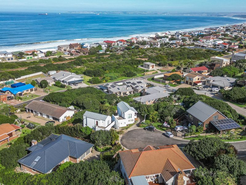 An aerial view of a coastal residential neighborhood, showcasing the property's location, surrounding homes, and proximity to the ocean.