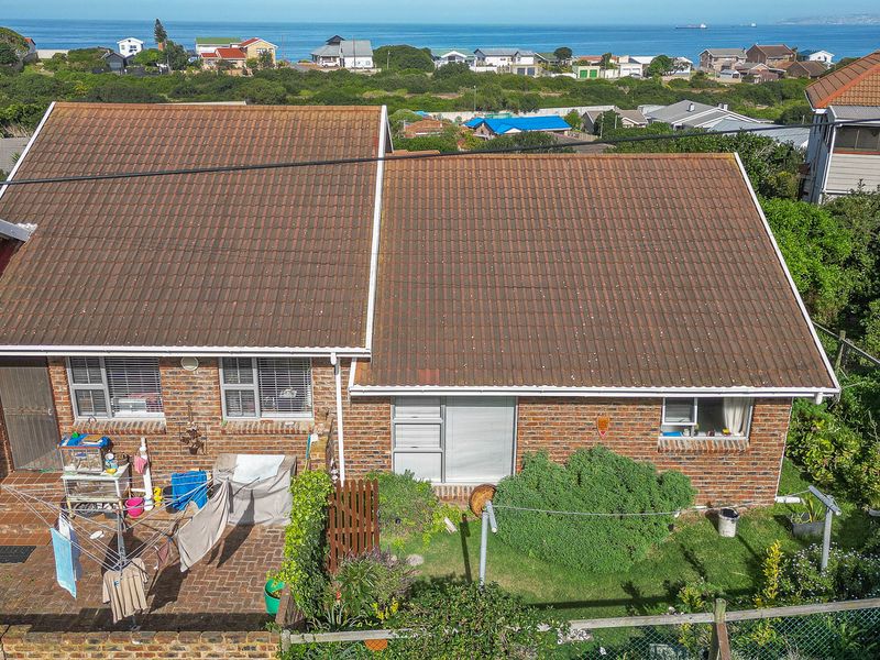 Aerial view of a duet property featuring a tiled roof, facebrick facade, and a paved rear patio area with coastal views.