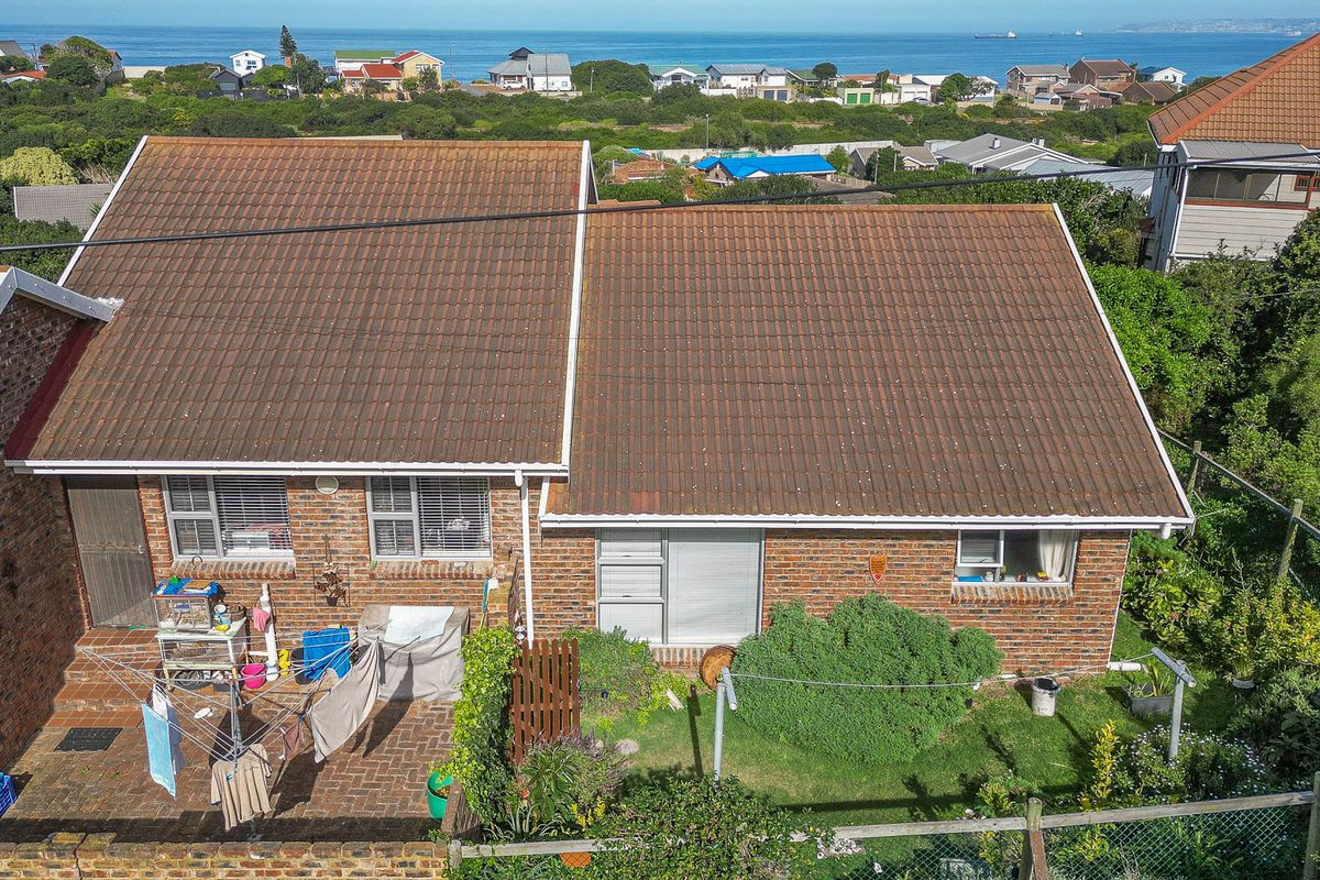 Aerial view of a duet property featuring a tiled roof, facebrick facade, and a paved rear patio area with coastal views.