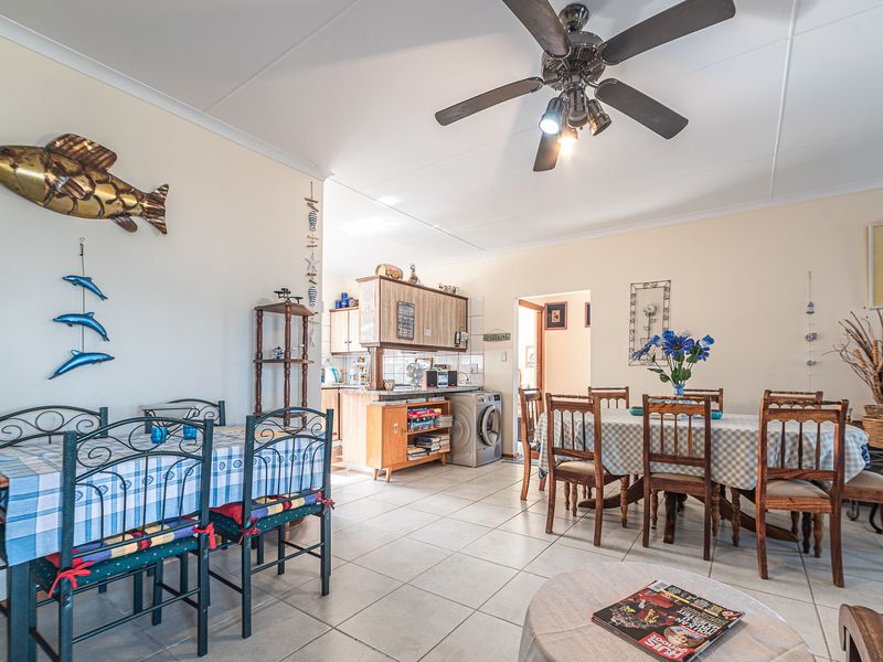 Open-plan living and dining area featuring tiled flooring, a ceiling fan, and an integrated kitchen space with cabinetry.