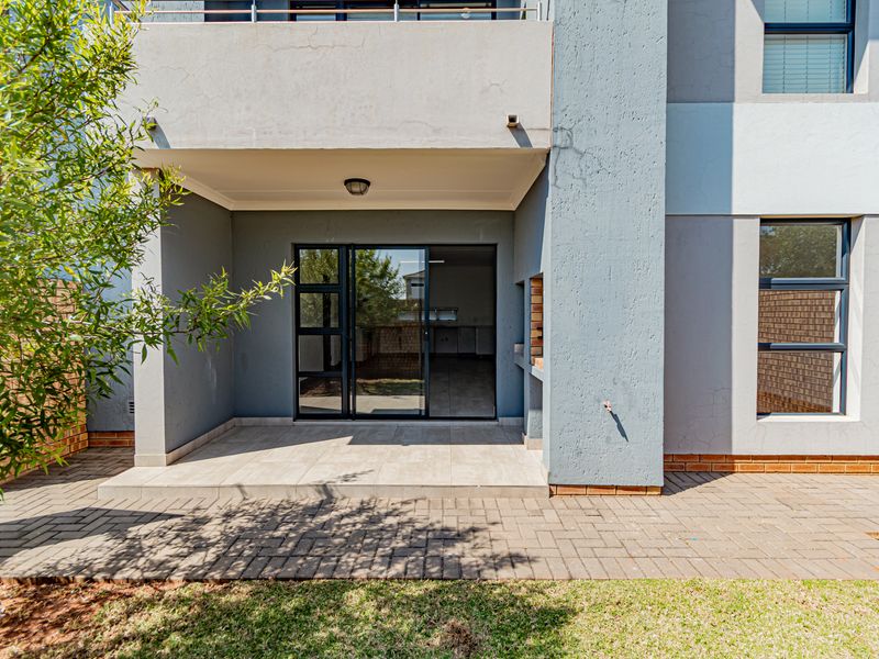 Covered patio area featuring a built-in braai, tiled flooring, and direct access to the interior through a sliding glass door.