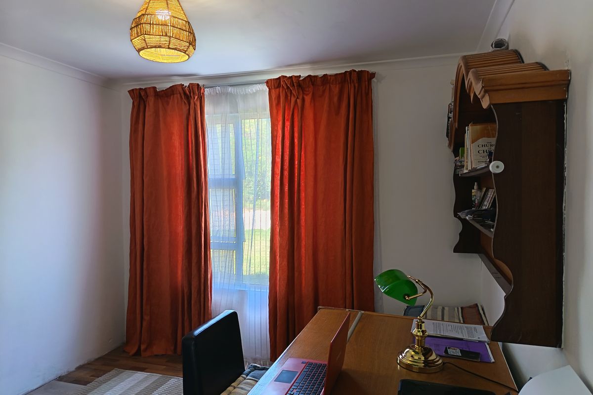 A functional bedroom space featuring laminate flooring, coving, and a window with natural light, suitable for use as a bedroom or home office.