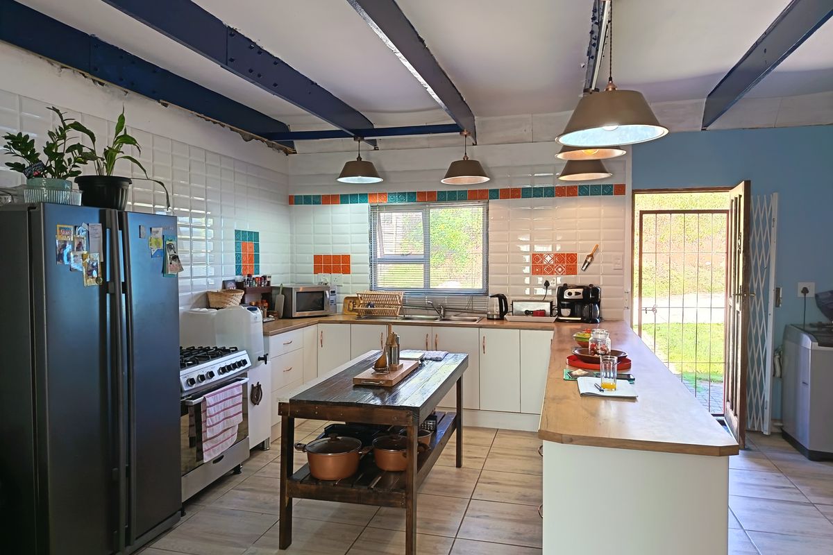 Spacious kitchen featuring white cabinetry, tiled backsplash, a central island, and exposed ceiling beams, with direct access to the exterior.