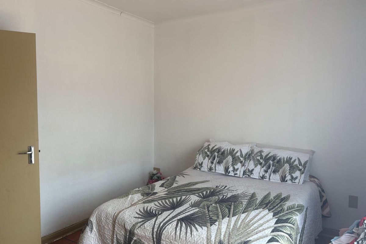 A simple bedroom featuring tiled flooring and a standard interior door, providing a functional and neutral living space.