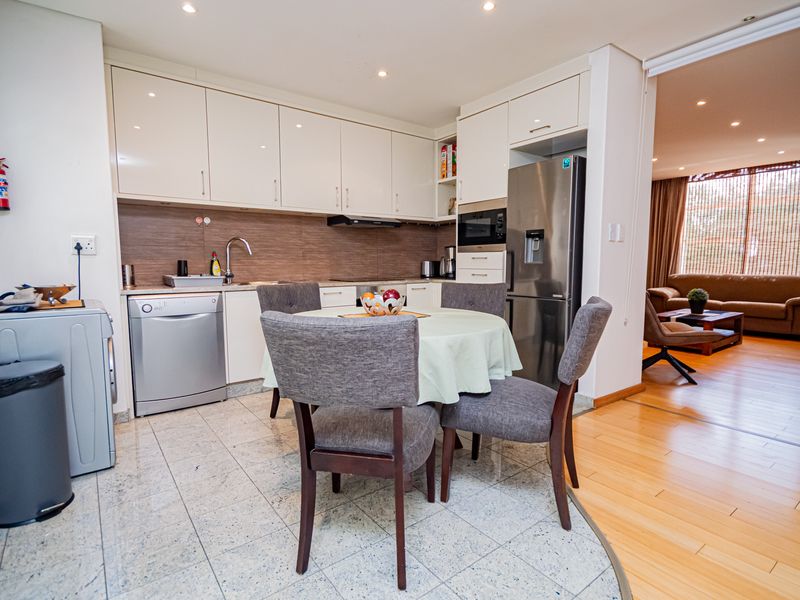 Open-plan kitchen and dining area featuring modern white cabinetry, tiled flooring, and seamless transition into the adjacent living space.