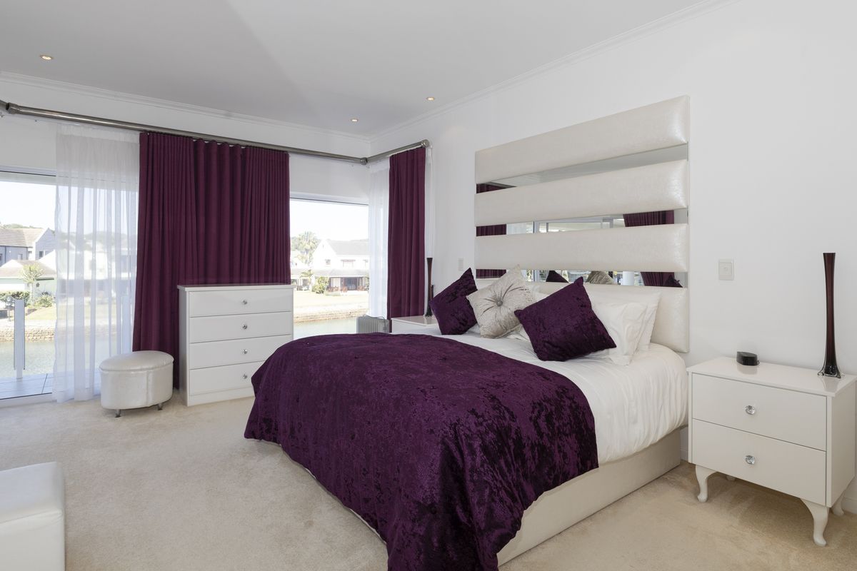 Spacious bedroom featuring neutral carpeting, recessed downlighting, and large sliding glass doors providing access to an outdoor area with water views.