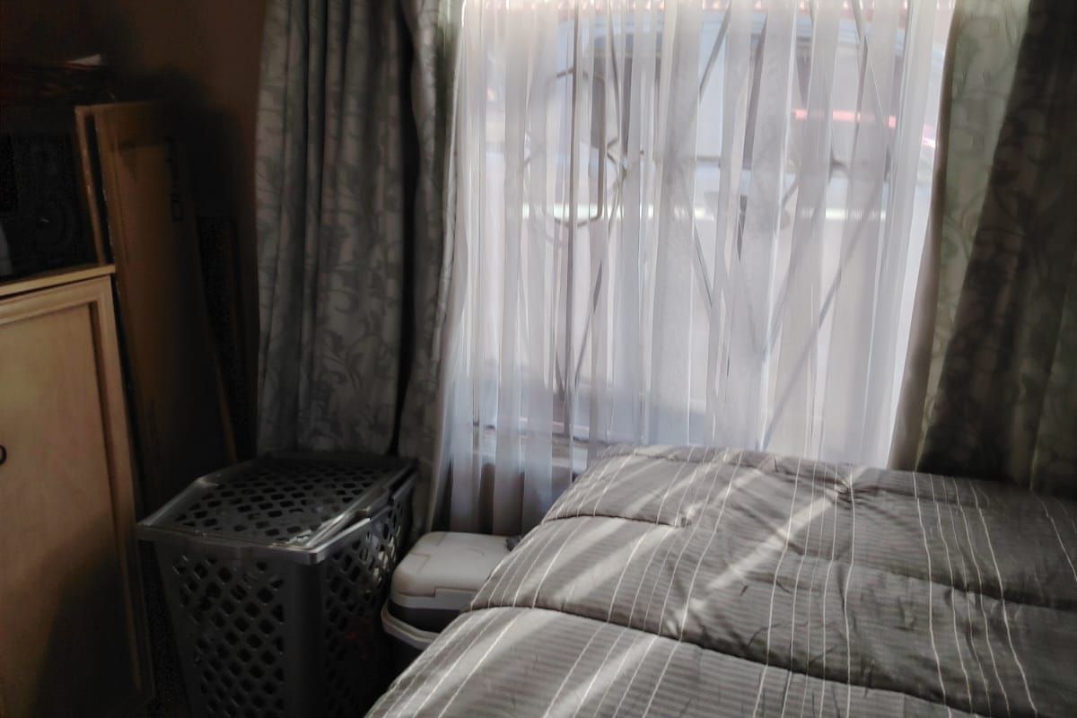 A bedroom featuring a window with a security gate and curtain tracks, providing natural light.